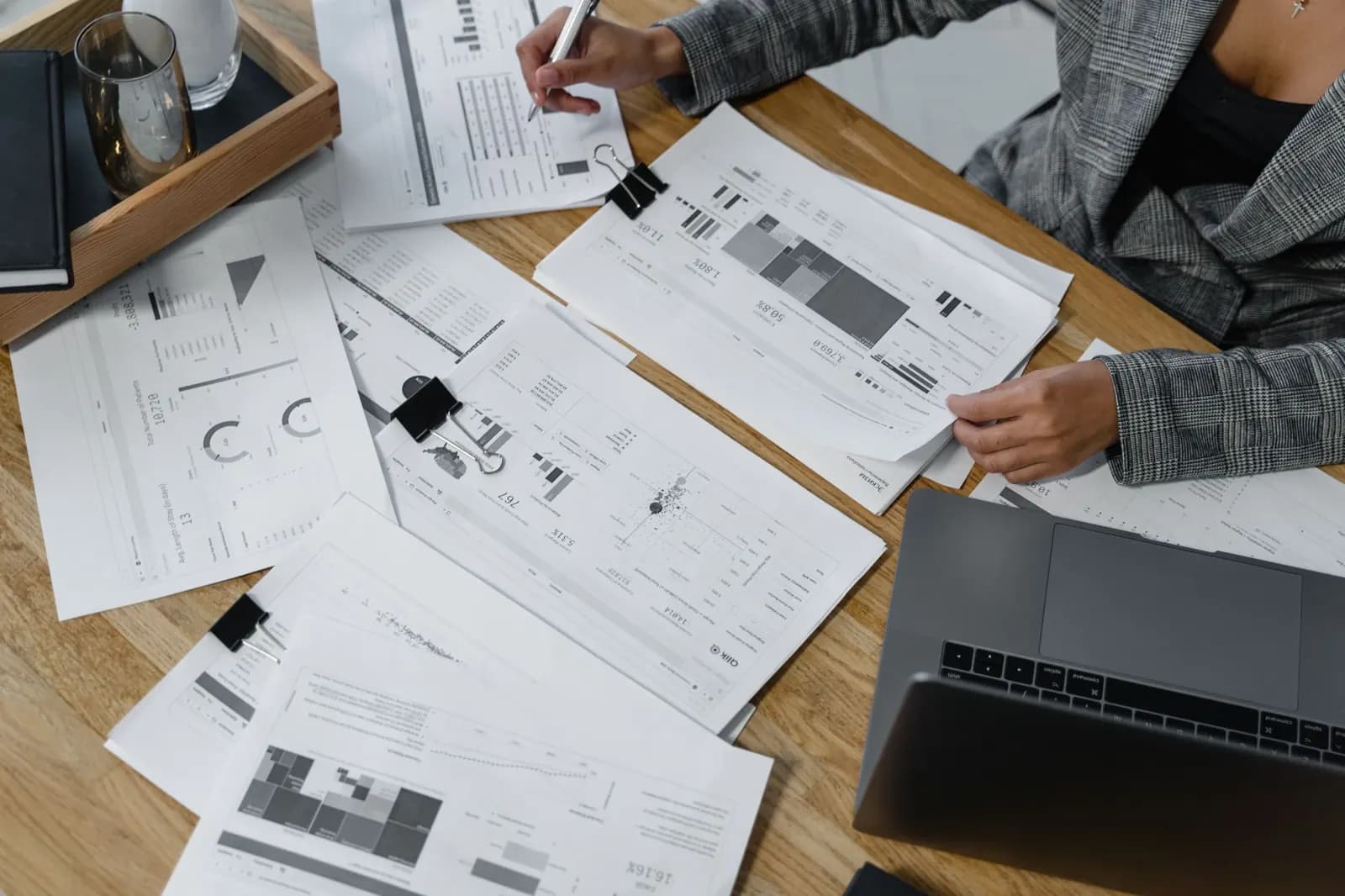 Des rapports imprimés et des ordinateurs éparpillés sur une table de travail.