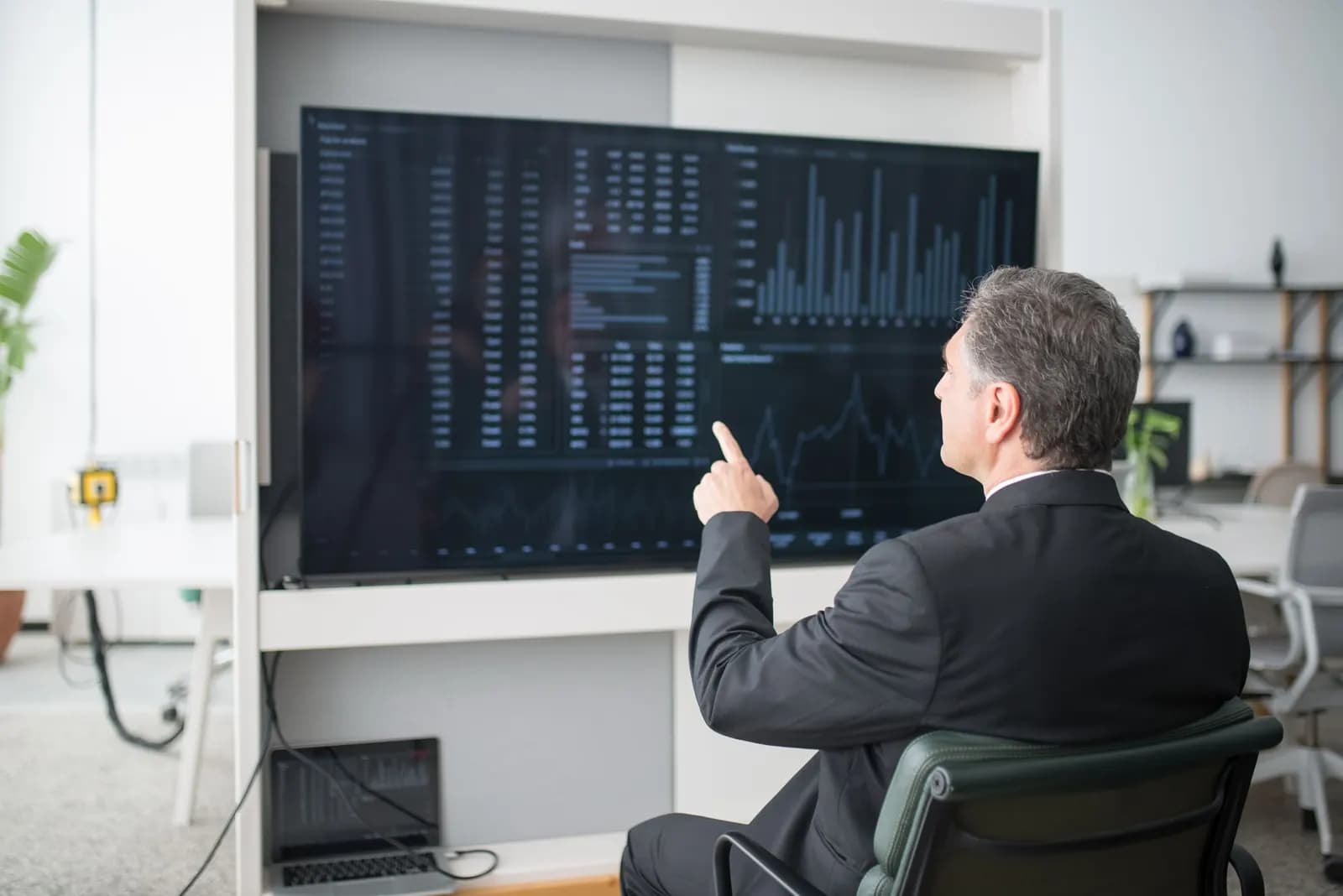 Un dirigeant analyse les indicateurs de l’entreprise affichés sur un grand écran.